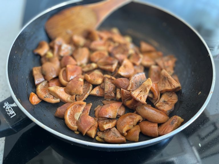 a frying pan filled with mushrooms on top of a stove