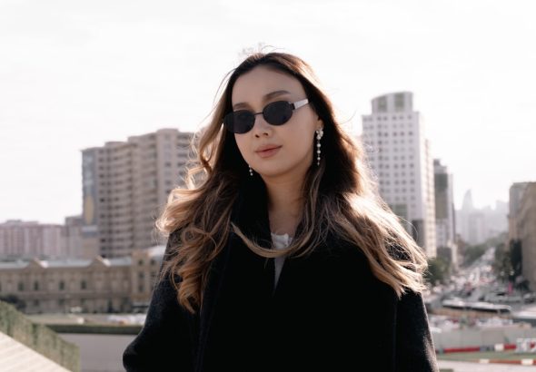 Stylish woman wearing sunglasses with city buildings behind.