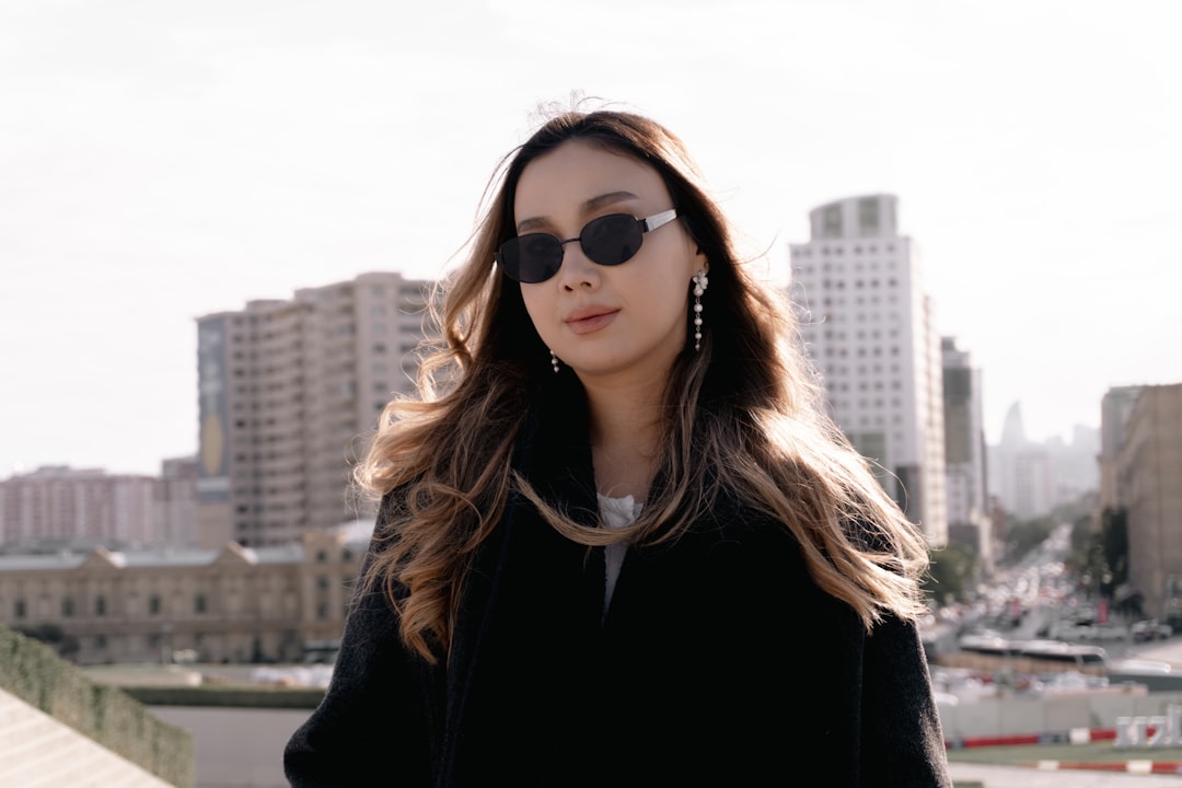 Stylish woman wearing sunglasses with city buildings behind.