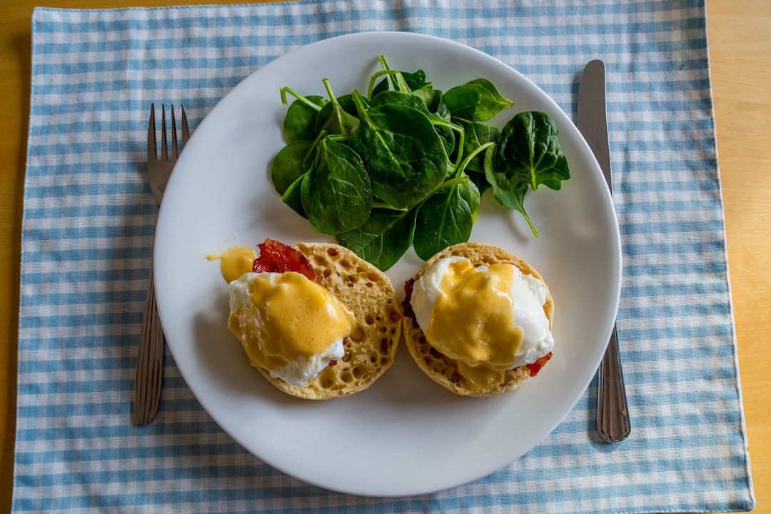 Eggs benedict with spinach on a checkered cloth.