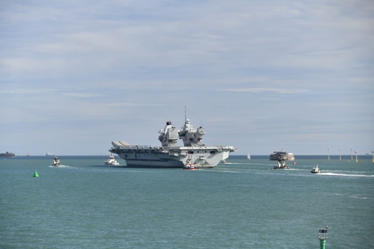 A large aircraft carrier sails on the ocean.