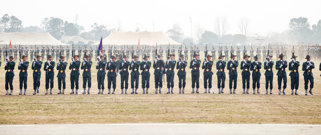 Soldiers in uniform stand at attention with rifles.