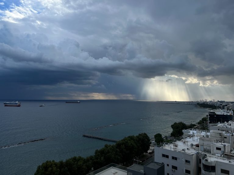 Sunbeams break through stormy clouds over the ocean.