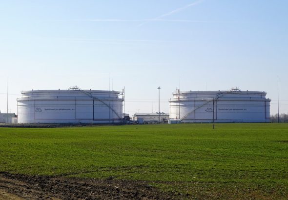 Two large white storage tanks in a field