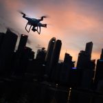 silhouette of quadcopter drone hovering near the city