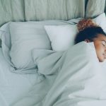 A young woman sleeping peacefully in a white bed