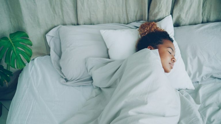 A young woman sleeping peacefully in a white bed